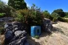 Trinkwassertank, teilweise hinter Natursteinmauer verborgen