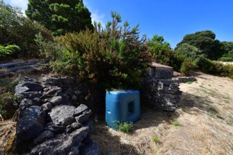 Trinkwassertank, teilweise hinter Natursteinmauer verborgen